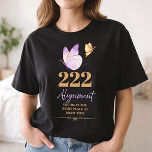 May include: Black t-shirt featuring a butterfly design with the text "222 Alignment". The design includes a purple butterfly, a smaller yellow butterfly, and the phrase "You're in the right place at the right time".