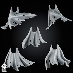 May include: Five light grey miniature capes with tattered, torn edges and flowing folds. Each cape features a distinct shape and varying degrees of damage along the bottom hem, designed for attachment to small scale figures or gaming models.