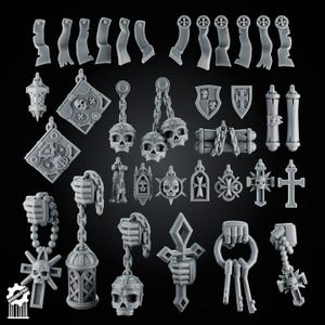 May include: A collection of grey miniature resin accessories featuring various gothic and religious motifs, including skulls, chains, shields, scrolls, lanterns, crosses, and hands holding keys or charms, arranged on a dark background with a logo.