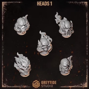May include: Five grey miniature heads labelled HEADS 1 by Greytide Studio. Each head features a unique design with flame-like protrusions, skull-like facial structures, and mechanical elements, presented against a dark background with embers.