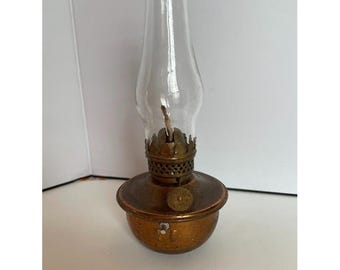 Lámpara de aceite miniatura vintage de latón con forma de dedo y pantalla de cristal transparente tipo huracán.