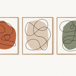 May include: A set of three ceramic mugs with a speckled, matte finish. The mugs are in shades of cream, light gray, and dark gray. Each mug has a simple, minimalist design and a rounded handle. Perfect for coffee or tea.