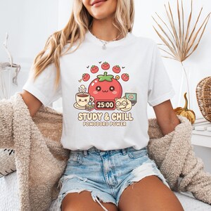 May include: White t-shirt with a colorful graphic featuring a smiling tomato, coffee cup, cat, and laptop. The text "STUDY & CHILL" and "POMODORO POWER" are below the graphic. The tomato has a timer set to 25:00.