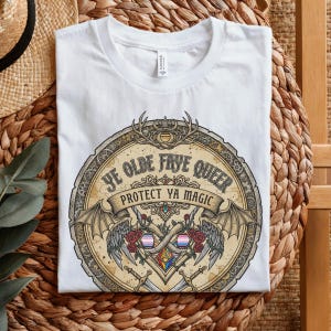 May include: White t-shirt with a circular graphic featuring the text "YE OLDE FAYE QUEER PROTECT YA MAGIC". The design includes wings, roses, swords, and a heart with the transgender pride flag colors.