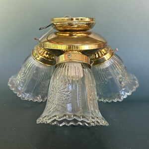 May include: A vintage ceiling light fitting with four clear glass shades. The shades have a scalloped edge and a starburst pattern. The fitting has a brass finish and is designed for ceiling mounting.