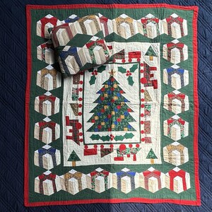 May include: A square quilt and matching throw pillow featuring a central Christmas tree applique on a cream background, surrounded by a border of gift box patterns in red, green, and tan fabrics, finished with a solid red outer trim.