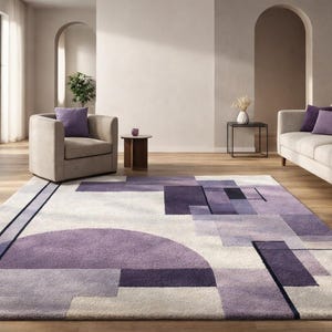 Può includere: Un moderno tappeto con un design geometrico nei toni del viola, grigio e bianco. Il tappeto presenta un grande semicerchio e forme rettangolari. Il tappeto è posto in un soggiorno con un divano, una poltrona e un tavolino.