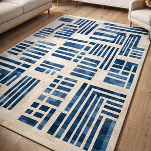 Peut inclure: Un tapis rectangulaire avec un motif géométrique dans des tons de bleu sur un fond beige. Le design présente une série de formes rectangulaires et linéaires, créant un aspect moderne et abstrait. Le tapis est posé sur un sol en bois.