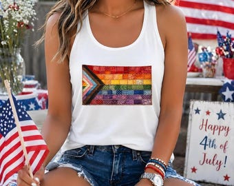 May include: A white tank top featuring a rectangular graphic of a pride flag composed of various colorful, patterned fabric squares. The design includes a chevron pattern on the left side with stripes of red, orange, yellow, green, blue, and purple.