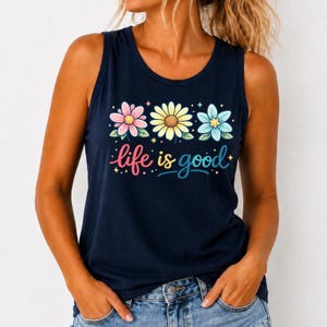 May include: Navy blue tank top with a floral design and the phrase "life is good" in colorful script. The top features three flowers in pink, yellow, and blue, with small star accents. A casual and cheerful summer top.