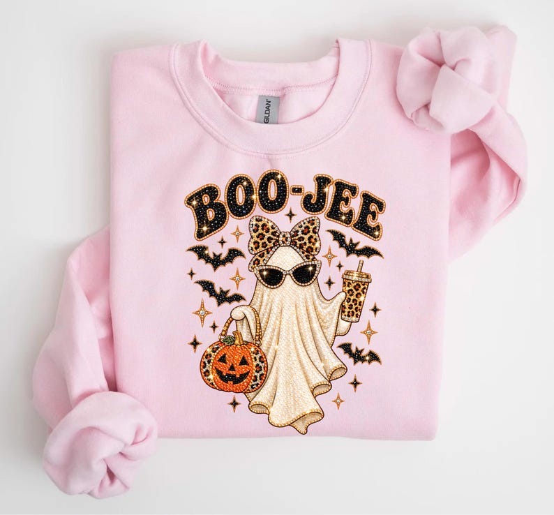 Pu&ograve; includere: Una felpa girocollo rosa chiaro con la grafica di un fantasma che indossa un fiocco e occhiali da sole leopardati. Il fantasma tiene in mano un bicchiere leopardato e un secchiello a forma di zucca. Il testo BOO-JEE &egrave; stampato sopra con pipistrelli.