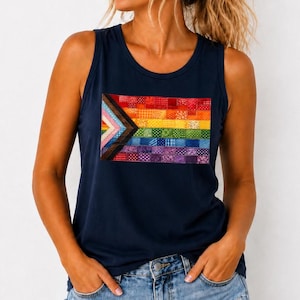 May include: A navy blue sleeveless tank top featuring a rectangular graphic print on the chest. The graphic is a patchwork-style pride flag composed of horizontal stripes in red, orange, yellow, green, blue, and purple, with a chevron triangle.