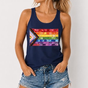 May include: A navy blue tank top featuring a rectangular graphic print of a pride flag composed of horizontal stripes in red, orange, yellow, green, blue, and purple, with a chevron pattern on the left side in black, brown, and white.