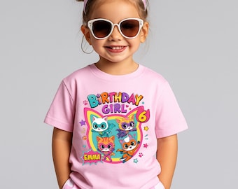 May include: A light pink short-sleeved t-shirt featuring a colorful graphic of four cartoon cats in superhero costumes. The text reads Birthday Girl, the number 6, and the name Emma. The design includes stars, paw prints, and a rainbow border.
