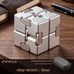 May include: A silver alloy fidget cube, approximately 1.6 x 1.6 x 1.6 inches, with a complementary high-end storage pouch. The cube is composed of multiple connected blocks with rounded edges. The text "Alloy Version: Silver" is visible.