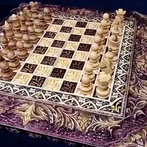 May include: A square chess set featuring a board with alternating dark brown and light cream squares, each decorated with intricate floral patterns. The board is surrounded by a wide, deeply carved purple frame with ornate leaf motifs.