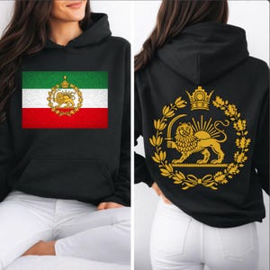 Puede incluir: Sudadera con capucha negra con la bandera iraní en la parte delantera y un emblema dorado en la parte trasera. El diseño de la bandera incluye rayas verdes, blancas y rojas con un emblema dorado. La parte trasera muestra un emblema dorado de león y sol.