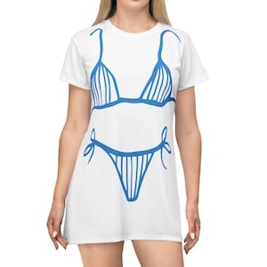 以下が含まれることがあります： 半袖の白いTシャツワンピースで、ビキニの大きな青いグラフィックプリントが施されています。このデザインは、三角形のトップとサイドで結ぶボトムスで構成されており、どちらも青い輪郭線と縦線のディテールが描かれています。