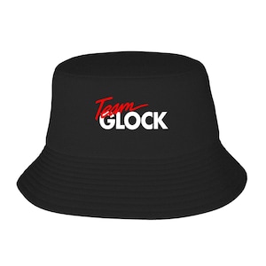 May include: Black bucket hat with the text "Team GLOCK" in red and white. The hat has a wide brim and a simple, classic design.