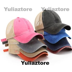 Pu&ograve; includere: Una pila di cappellini da camionista in vari colori, tra cui rosa, grigio e blu. Ogni cappellino presenta un retro in rete e una visiera curva. Il testo "Yuliazstore" &egrave; stampato sull'immagine.