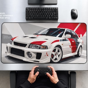 Pode incluir: Um tapete de secretária retangular com um carro de rali Mitsubishi Lancer Evolution branco com detalhes gráficos vermelhos e cinzentos. O design inclui o texto TRONULUS PLAYER DEPARTMENT NOT FOR NPCS numa superfície metálica.