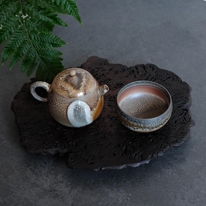 May include: A ceramic teapot and a matching bowl featuring a mottled glaze in shades of brown, beige, and white. The teapot has a rounded body, a small lid, and a curved handle. The bowl has a wide opening with a gradient interior finish.