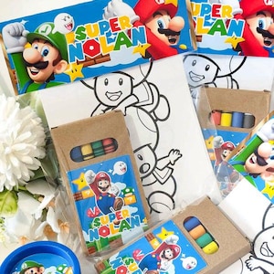 Peut inclure: Un ensemble de cadeaux de fête avec des personnages de Super Mario et le texte Super Nolan. Les articles comprennent des boîtes en carton brun contenant des petits crayons, des feuilles de coloriage avec des contours de Toad et un pot bleu.