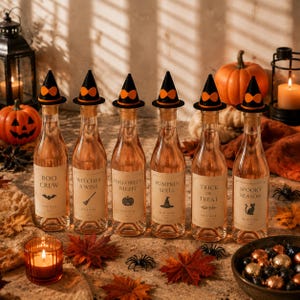 May include: Six clear glass wine bottles filled with rose wine, each topped with a miniature black witch hat. The labels feature Halloween-themed text including Boo Crew, Witches & Wine, Halloween Night, Pumpkin Spell, Trick or Treat, and Spooky Season.