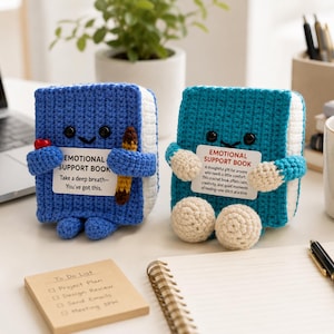 May include: Two crocheted book figures with smiling faces and black bead eyes. The blue book holds a pencil and a sign reading EMOTIONAL SUPPORT BOOK Take a deep breath—You've got this. The teal book holds a sign reading EMOTIONAL SUPPORT BOOK.