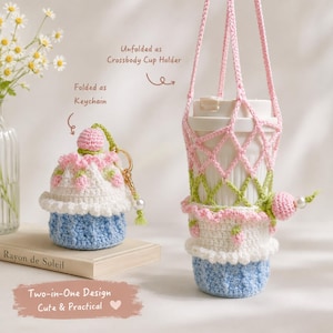 Pode incluir: Um item de crochê em duas formas: dobrado como chaveiro e desdobrado como porta-copos transversal. O design apresenta uma base azul clara, meio branco e detalhes de morango rosa. O texto inclui "Unfolded as Crossbody Cup Holder," "Folded as Keychain," e "Two-in-One Design Cute & Practical."