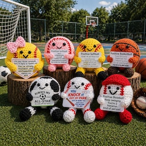 Peut inclure: Divers ballons de sport crochetés, dont un de baseball, de softball, de basket-ball et de football, chacun avec un visage souriant et un message de motivation. Les ballons sont jaunes, roses, oranges, blancs et noirs.