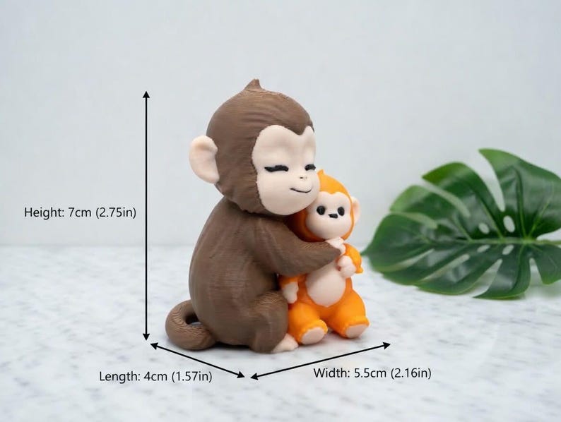 Pode incluir: Uma estatueta de macaco castanho e laranja, com 7 cm de altura, abra&ccedil;ando um macaco laranja menor. A estatueta tem 4 cm de comprimento e 5,5 cm de largura. Os macacos t&ecirc;m rostos sorridentes e est&atilde;o sobre um fundo claro.