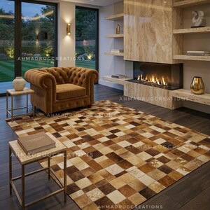 Può includere: Un grande tappeto rettangolare caratterizzato da un patchwork di piastrelle quadrate in varie tonalità di marrone, beige e crema. Il tappeto è posizionato su un pavimento in legno scuro in una stanza con poltrona marrone, camino e tavolini.