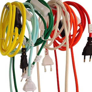 Può includere: Una collezione di cavi elettrici colorati con spine. I cavi sono in vari colori, tra cui giallo, azzurro, verde, bianco e arancione. Ogni cavo ha un filo rivestito in tessuto abbinato e una spina bianca o nera. I cavi sono ad anello e disposti su uno sfondo bianco.