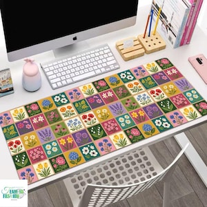 May include: A colorful floral desk mat featuring a grid of various flower illustrations in square blocks. The mat is rectangular and sits on a white desk, with a computer, keyboard, and other office supplies visible.