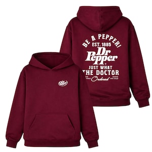 May include: Maroon hoodie with a front pocket and hood. The front features a small Dr. Pepper logo, while the back displays the Dr. Pepper logo and the text "BE A PEPPER! EST. 1885 JUST WHAT THE DOCTOR Ordered SERVE ICE COLD."