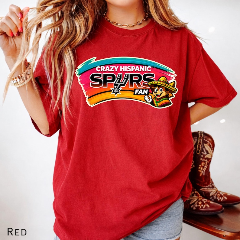 Op de afbeelding: Rood t-shirt met een kleurrijke afbeelding met de tekst "Crazy Hispanic Spurs Fan". De afbeelding toont een cartoonfiguur met een sombrero. Het woord "RED" staat linksonder op het shirt.