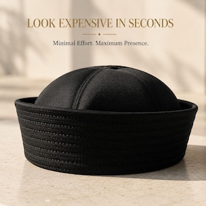May include: A black brimless cap featuring a rounded crown with stitched panels and a wide, multi-stitched band. The text above the cap reads LOOK EXPENSIVE IN SECONDS and Minimal Effort. Maximum Presence. The cap has a structured, solid black design.