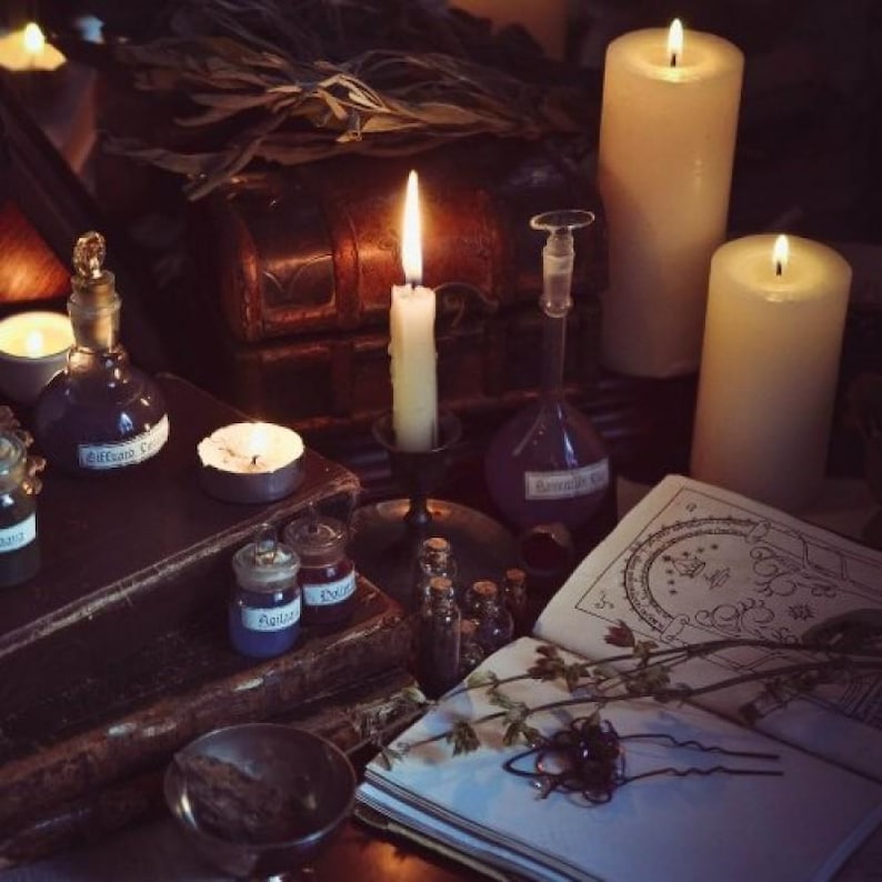 May include: A dimly lit scene featuring candles, books, and potion bottles. Several lit candles of varying sizes illuminate the scene. Small glass bottles and jars with labels sit on a dark wooden surface, alongside an open book and dried herbs.