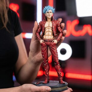 Pode incluir: Figura detalhada de um personagem de anime com cabelo azul espetado, vestindo uma jaqueta e calças vermelhas adornadas com tachas prateadas. O personagem tem um físico musculoso e posa com as mãos nos bolsos. A figura está em uma base circular.