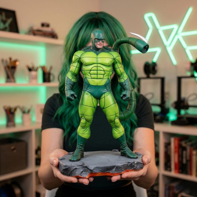 May include: A green and dark green Scorpion action figure. The figure is standing on a gray, rocky base with an orange glow. The figure has a tail with a white stinger. The figure is a collectible item.