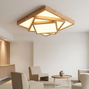 Puede incluir: Una moderna lámpara de techo geométrica con marco de madera y paneles luminosos integrados. La luz tiene un diseño en capas, con formas rectangulares y triangulares. La lámpara está instalada en una habitación con muebles de tonos neutros.