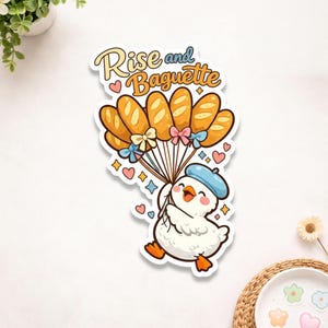 May include: A sticker featuring a cartoon duck wearing a blue beret, holding baguettes tied with bows. The text "Rise and Baguette" is above the baguettes. Hearts and stars surround the duck, creating a whimsical design.