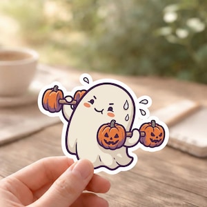 May include: A sticker featuring a cartoon ghost lifting pumpkin weights. The ghost is white with a smiling face and sweat droplets. The pumpkins are orange with carved jack-o'-lantern faces. A fun Halloween-themed design.