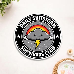 May include: A round sticker with the text "DAILY SHITSTORM SURVIVORS CLUB" in a black and white circular design. The design includes a gray cloud with a rainbow and a yellow lightning bolt.