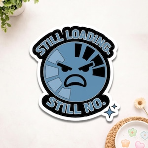 May include: A sticker with the text "STILL LOADING. STILL NO." in a black and blue design. The sticker features a blue loading symbol with an angry face. A small, blue star is also visible.
