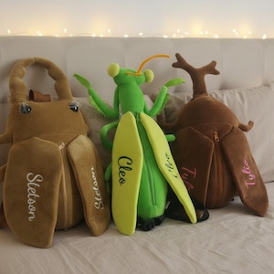 May include: Three plush insect-shaped backpacks featuring a tan beetle with the name Stetson, a bright green praying mantis with the name Cleo, and a brown stag beetle with the name Tyler. Each soft bag includes a zipper closure and straps.