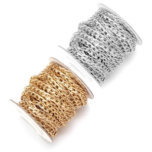 May include: Two spools of chain, one gold-colored and one silver-colored, are displayed against a white background. The chains are made of interconnected links, suitable for jewelry making or other crafts. The spools are on a slight angle.