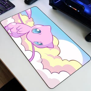 May include: Rectangular mouse mat featuring a pink cartoon character with large blue eyes, floating among pastel-coloured clouds against a blue sky. The design is a vibrant illustration, suitable for a computer setup.