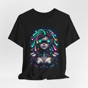 May include: Black t-shirt featuring a futuristic illustration of a woman with neon-colored hair and a visor. The artwork depicts a cybernetic theme with vibrant green, blue, and pink accents, creating a striking visual on the tee.